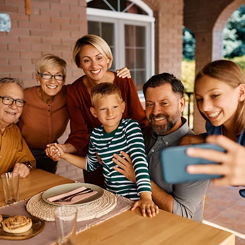 A multigenerational family, ranging from young children to grandparents, grouped together and posing for a picture outside, reflecting their familial bonds, shared joy, and the beauty of an outdoor setting.
